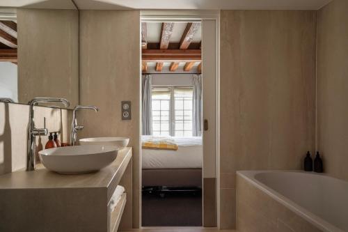 ein Badezimmer mit zwei Waschbecken, einer Badewanne und einem Bett in der Unterkunft L'Absinthe Hôtel in Honfleur