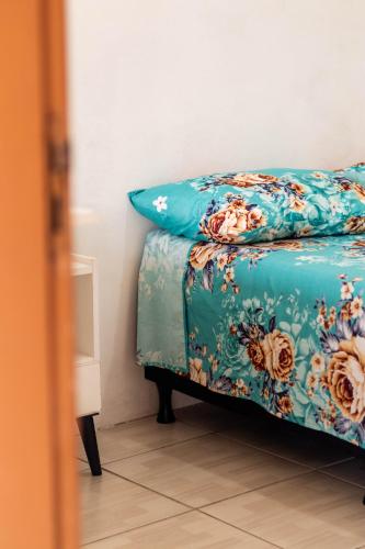 a bed with a blue blanket with flowers on it at Pousada recanto do mar torres Itapeva norte in Torres