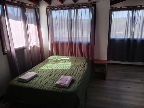 a bedroom with a green bed with two towels on it at Altos de el bolson in El Bolsón
