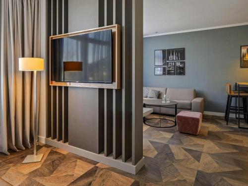 un salon avec un canapé et une télévision fixée au mur dans l'établissement Mercure Hotel Koeln Belfortstrasse, à Cologne