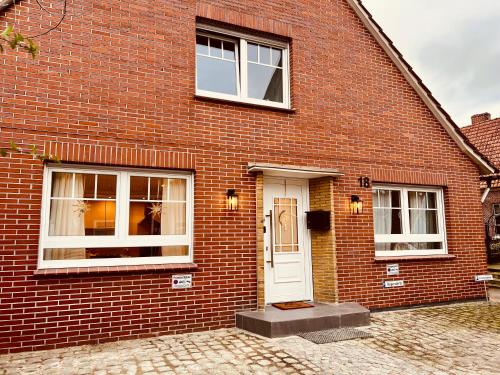 ein Backsteinhaus mit einer weißen Tür und Fenstern in der Unterkunft Ferienwohnung auf dem Berg in Bad Bentheim