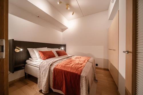 a bedroom with a bed with an orange blanket on it at Levillas Lingonberry D26 in Levi