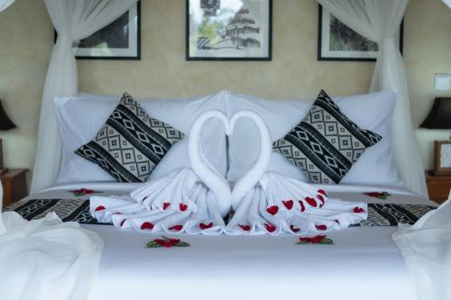 twee handdoeken in hartvorm op een bed bij Akar Villa in Ubud
