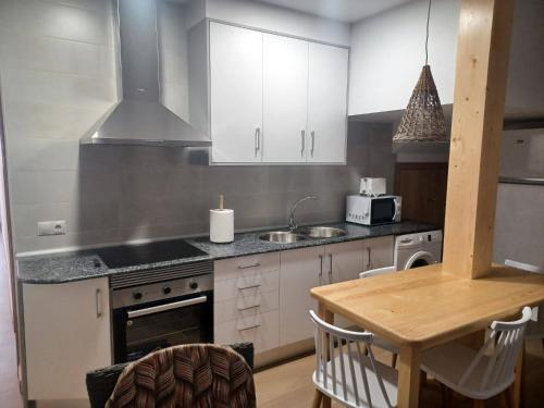 een keuken met witte kasten en een houten tafel bij La Casita in Tejadillos