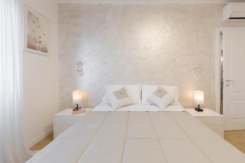 a white bedroom with a large white bed with two lamps at Smart Flat - Easy Milan Link in Cinisello Balsamo