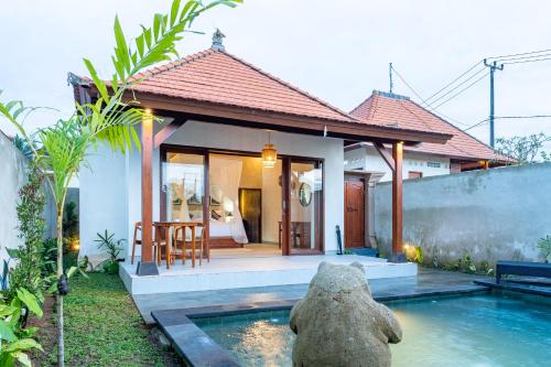 een klein huis met een zwembad ervoor bij Akar Villa in Ubud