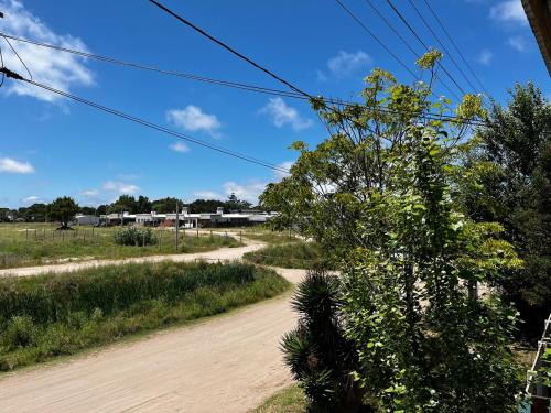 una strada sterrata in un campo con un albero di Altamare Villa Gesell a Villa Gesell