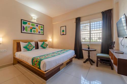 a bedroom with a bed and a desk and a window at Treebo Akshaya Palace Inn in Mysore