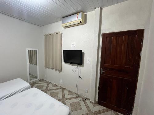 a bedroom with a bed and a tv and a door at Pousada Estilo Brasil in Fortaleza