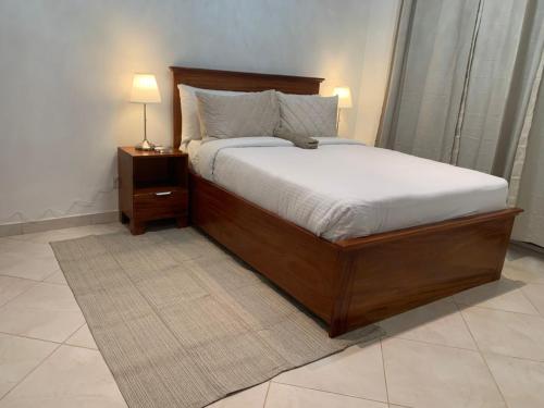 ein Schlafzimmer mit einem großen Bett und einem Nachttisch mit einer Lampe in der Unterkunft Haven Seven Property - 1 bedroom, 2 bedroom, 3 bedroom Executive options in Takoradi