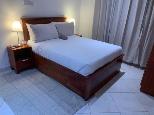 ein Schlafzimmer mit einem Bett und einem Nachttisch mit einer Lampe in der Unterkunft Haven Seven Property - 1 bedroom, 2 bedroom, 3 bedroom Executive options in Takoradi