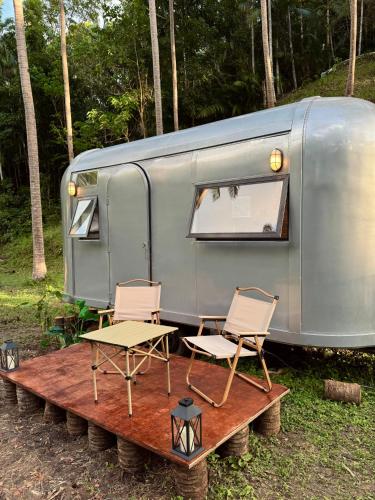 a trailer with two chairs and a table in front of it at Anora Eco-Resort Siquijor in Lazi