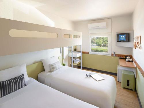 a hotel room with two beds and a desk at ibis Budget - Newcastle in Newcastle