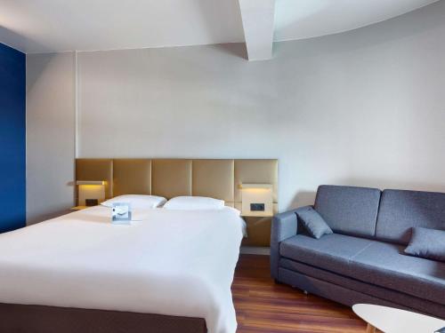 een hotelkamer met een bed en een bank bij ibis budget La Roche Sur Yon Vendespace in Mouilleron-le-Captif