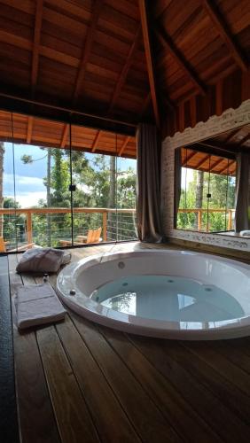 a large bath tub in a room with windows at Chalés Descanso na Serra in Monte Verde