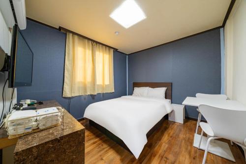 ein Schlafzimmer mit einem großen weißen Bett und einem Schreibtisch in der Unterkunft 귀빈모텔 in Donghae