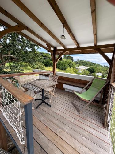 eine Terrasse mit Tisch und Stühlen auf einem Deck in der Unterkunft La cabane in Le Vauclin
