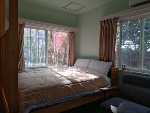 a bedroom with a bed and two large windows at Nemurupa Garden Hostel and Yoga near Narita Airport 15 min Late Check in in Narita