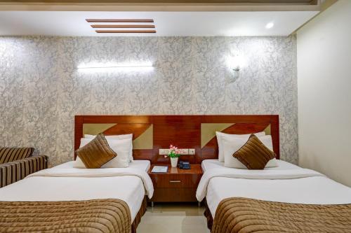 a hotel room with two beds and a chair at Hotel B Stays in Gurgaon