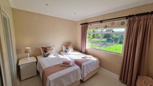 a bedroom with two beds and a window at Flanders South Cottage in Gqeberha