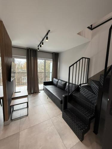 - un salon avec un canapé noir et des escaliers dans l'établissement Property Apart - Work & Stay Suites, à Wrocław