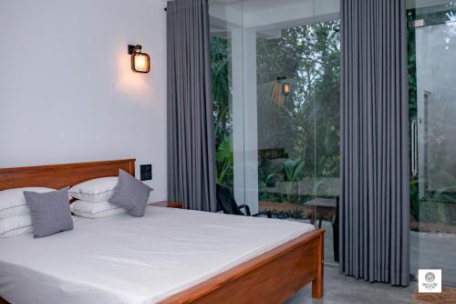 a bedroom with a bed and a large window at Willow Waters in Galle