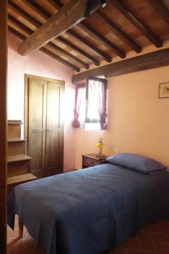 een slaapkamer met een blauw bed in een kamer met houten plafonds bij Torre Verde Acquapendente in Acquapendente