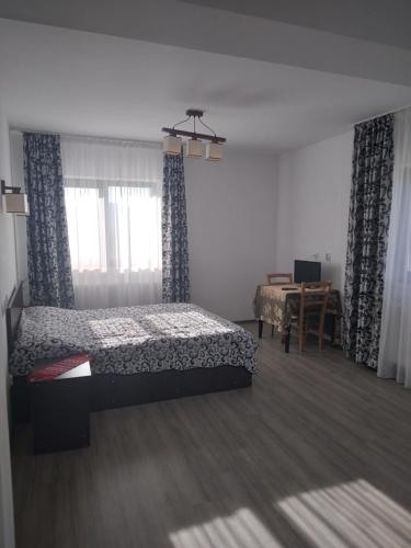 una camera da letto con un letto, una scrivania e una finestra di Pensiunea Drumul Voievozilor a Arefu