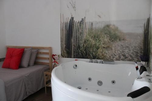 a bathroom with a white bath tub next to a bed at Cottage Cilento B&B in Trentinara