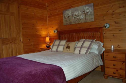 ein Schlafzimmer mit einem Bett in einer Blockhütte in der Unterkunft Woodland Oak Log Cabin, by Meall nan Tarmachan in Killin