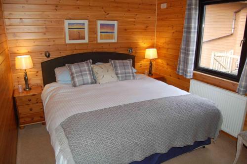 a bedroom with a large bed in a wooden room at Woodland Oak Log Cabin, by Meall nan Tarmachan in Killin