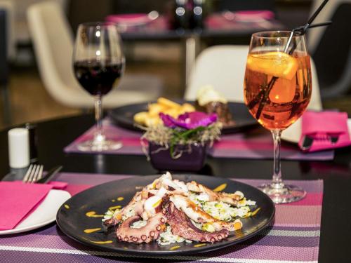 a table with two plates of food and two glasses of wine at Mercure Bucharest City Center in Bucharest