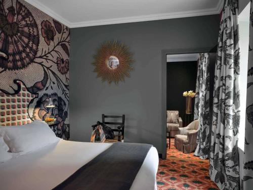 a bedroom with a bed with a painting on the wall at Jules César Hotel & Spa Arles - MGallery Collection in Arles