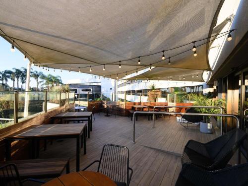 a patio with tables and chairs on a balcony at Mercure Penrith in Penrith