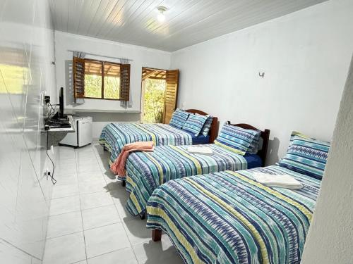 een kamer met drie bedden en een wastafel. bij Pousada Maré in Ponta do Mel