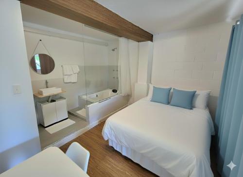ein Schlafzimmer mit einem weißen Bett und ein Badezimmer in der Unterkunft SUITES - Românticas na natureza para adultos in Itapecerica da Serra
