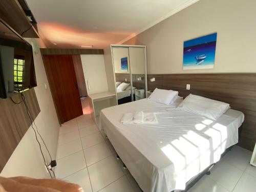 a bedroom with a large white bed and a television at AP Beira da Lagoa da Conceição in Florianópolis