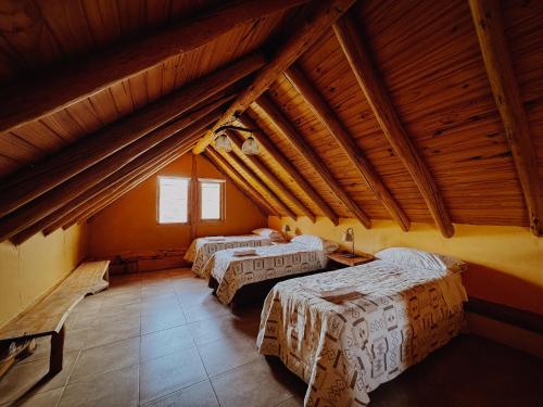 drie bedden in een kamer met houten plafonds bij Cabañas Aike in Caviahue