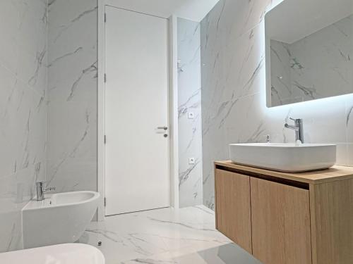 a white bathroom with a sink and a toilet at Prince Delmar Waterfront Olhao by Junto ao Mar in Olhão