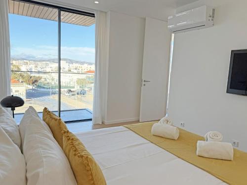 a bedroom with a large white bed and a large window at Prince Delmar Waterfront Olhao by Junto ao Mar in Olhão