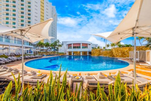 a pool with chairs and umbrellas at a resort at Krystal Grand Cancun All Inclusive in Cancún