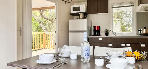 een keuken met een tafel met glazen en een magnetron bij La Vetta Village Vacances Camping in Porto-Vecchio