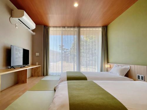 a hotel room with two beds and a large window at Kansai Airport Hotel Pine Villa in Kansai International Airport