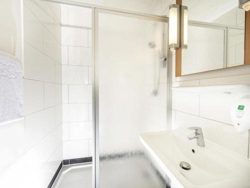a white bathroom with a shower and a sink at ibis Leipzig Nord-Ost in Leipzig