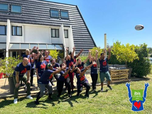 een groep mensen die in het gras staan met hun handen in de lucht bij Ibis Styles Toulouse Labège in Labège