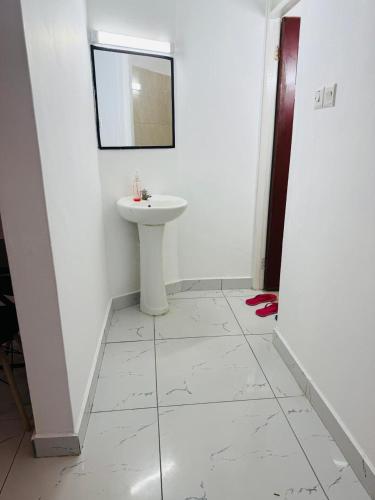 a white bathroom with a sink and a mirror at Casses Apartments in Mombasa