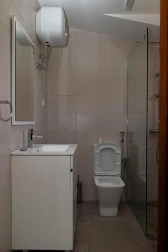 a bathroom with a toilet and a sink and a shower at FADIAS Quartos - Rooms in Ribeira Grande