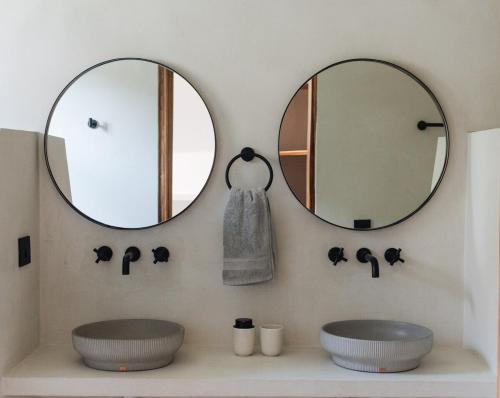 twee wastafels in een badkamer met twee spiegels bij Gaia Casa de Mar in El Bobo