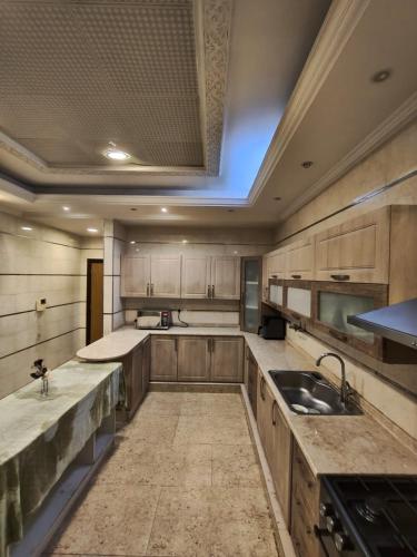 a large kitchen with wooden cabinets and a sink at Huge luxury villa stay with private room in Ajman
