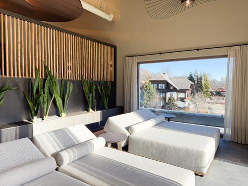 een woonkamer met witte meubels en een groot raam bij Aktivhotel Pehab - Dachstein Rooftop-Spa in Ramsau am Dachstein